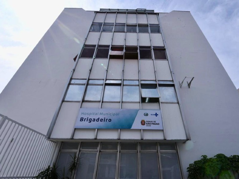 Fachada do Hospital Municipal Brigadeiro mostra o prédio de cinco andares, suas janelas e porta de entrada. Acima da porta há uma placa com o nome Hospital Municipal Brigadeiro, o símbolo do SUS e da Cidade de São Paulo